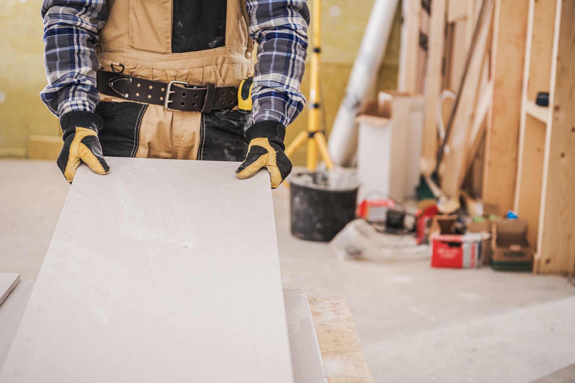 male contractor holding piece of drywall material